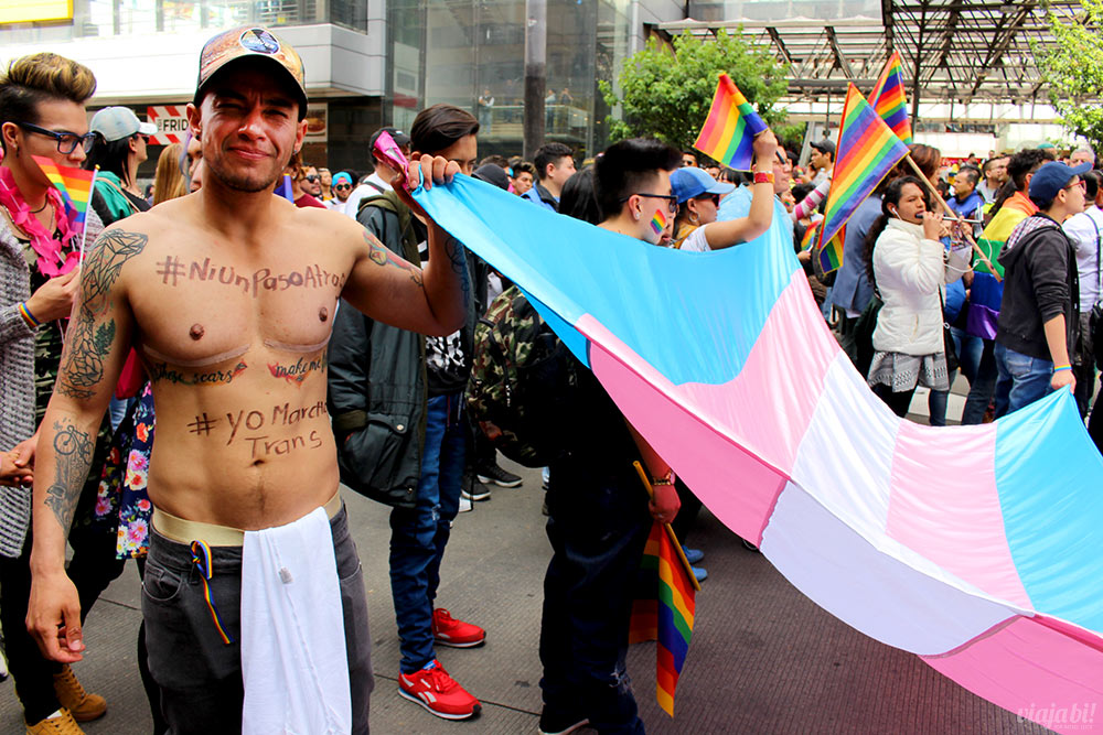 Homem trans segura bandeira na Marcha del Orgullo de Bogotá